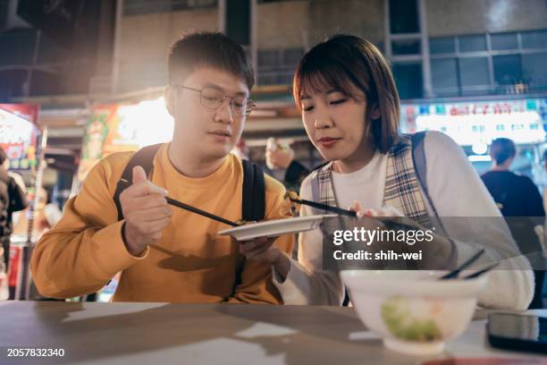 a young asian couple visited a famous local night market and tasted street food in taiwan - street light banner stock pictures, royalty-free photos & images