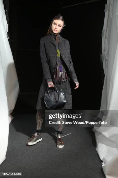 Backstage at the Cividini show during Milan Fashion Week Autumn/Winter 2016/17, a model wears a grey tweed checked skirt suit, layered over a ribbed...