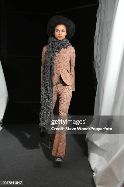 Backstage at the Cividini show during Milan Fashion Week Autumn/Winter 2016/17, a model wears a fitted camel coloured trouser suit in a scribbled...