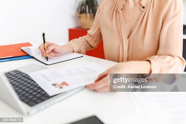 close up view of female hr recruiter taking notes while reading job applicant resume in the office. - candidato imagens e fotografias de stock