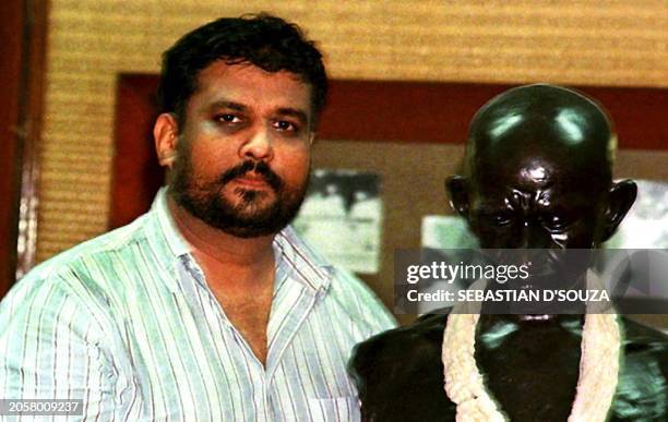 Tushar Gandhi, great grandson of Mahatma Gandhi, stands beside a bust of his great grandfather after announcing 17 January in Bombay, India that he...