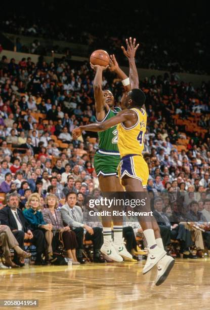 Mark Aguirre, Small Forward for the Dallas Mavericks attempts a three point jump shot to the basket as Mike McGee, Small Forward and Shooting Guard...