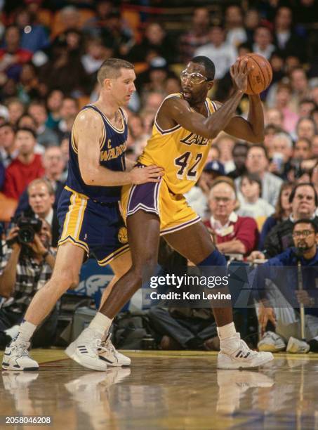 James Worthy, Small Forward and Power Forward for the Los Angeles Lakers inbounds the basketball under the challenge of Chris Mullin, Point Guard and...