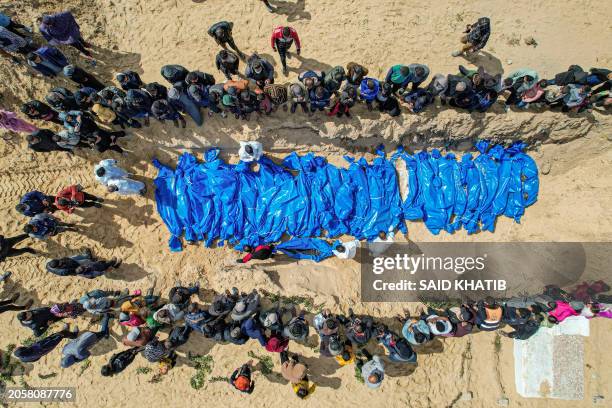 An aerial view shows mourners watching as medical personnel prepare the bodies of 47 Palestinians, that were taken and later released by Israel,...