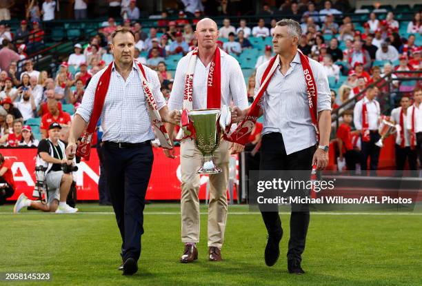 Jude Bolton, Barry Hall and Leo Barry hold the 2005 Premiership Cup during the 2024 AFL Opening Round match between the Sydney Swans and the...