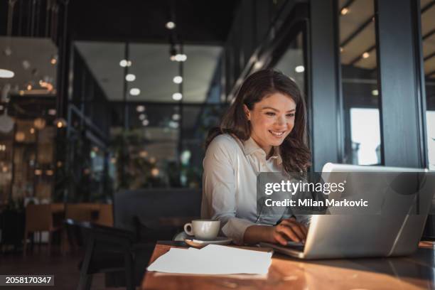 portrait of a beautiful business woman sitting in a cafe using a laptop and enjoying her favorite coffee - entrepreneur stock pictures, royalty-free photos & images