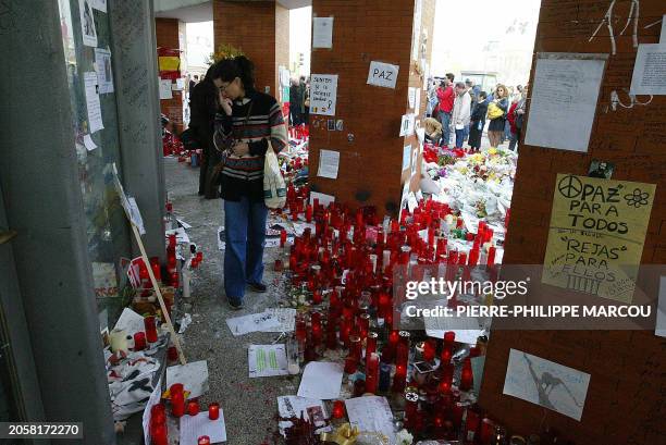 People gather around candles and flowers during a ceremony in memory of the victims of the blasts at Atocha train station, 18 March 2004 in Madrid, a...