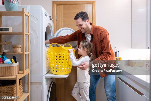 caucasian father and daughter, taking out the clothes from the dryer - droger stockfoto's en -beelden