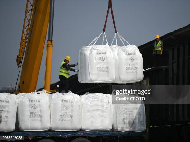 Crane is unloading fertilizer from a cargo train onto a truck at the freight yard of Southern Railway Xiangtangxi Station in Nanchang, Jiangxi...