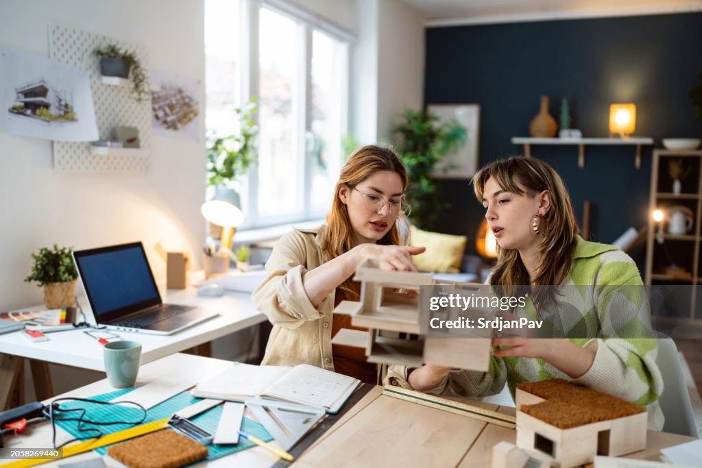 Two female architecture students making architectural model of a modern house