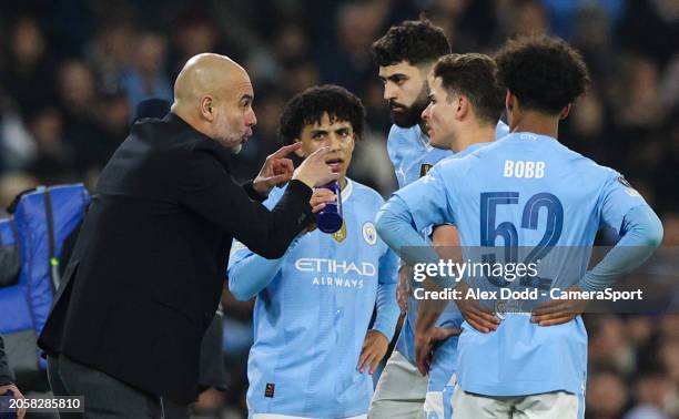 Manchester City manager Pep Guardiola speaks to his players during a break in play in the UEFA Champions League 2023/24 round of 16 second leg match...