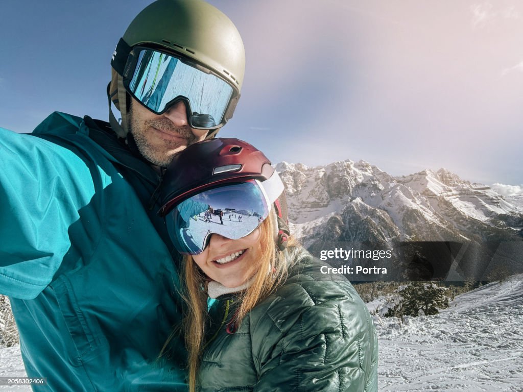 Lovely couple taking selfie on the mountain in ski resort
