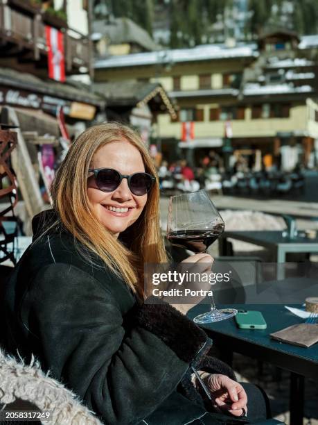 happy mature woman drinking wine and having fun at ski resort outdoors cafe - apres ski lunch stock pictures, royalty-free photos & images