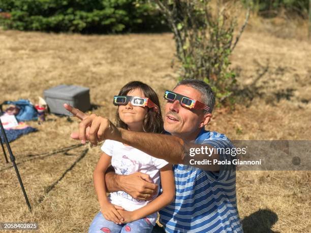 father and daughter looking at the sun during a solar eclipse on a country park, family outdoor activity - eclipse imagens e fotografias de stock