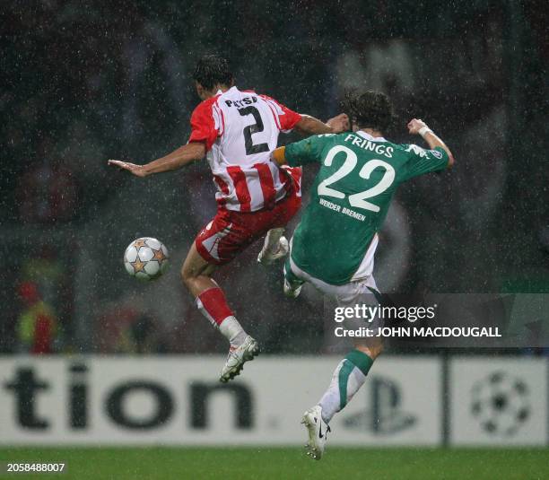 Olympiacos' defender Christos Patsatzoglou vies for the ball against Werder Bremen's midfielder Torsten Frings under the pouring rain during the...
