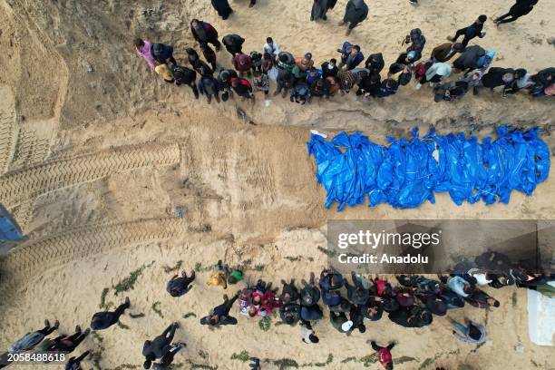 The bodies of 47 Palestinians delivered by Israeli forces from the Kerem Shalom border crossing are buried by opening the mass grave after funeral...