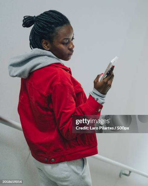 young woman using smart phone while standing against wall,corpus christi,texas,united states,usa - corpus christi stock pictures, royalty-free photos & images