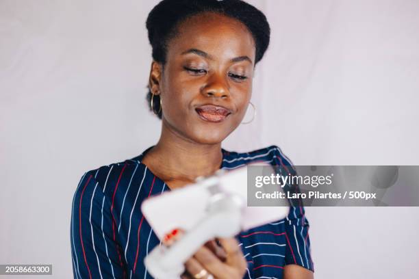 young woman holding smart phone against white background,corpus christi,texas,united states,usa - corpus christi stock pictures, royalty-free photos & images
