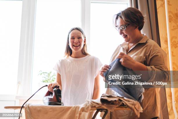 teenage girl with her middle aged mother ironing clothes in living room at home,yekaterinburg,sverdlovsk oblast,russia - teen packing suitcase stock pictures, royalty-free photos & images
