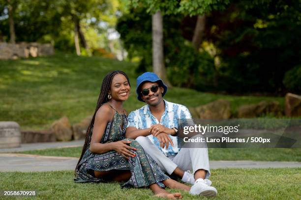 portrait of young couple sitting on grass smiling towards camera in garden,dallas arboretum and botanical garden,texas,united states,usa - peel park stock pictures, royalty-free photos & images