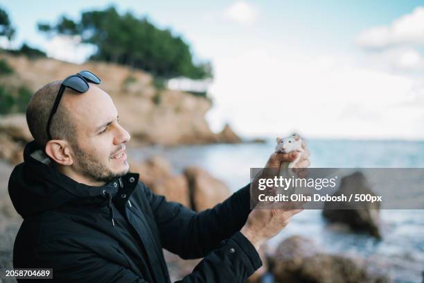 man holding seashell while standing at beach,tarragona,spain - tarragona province stock pictures, royalty-free photos & images