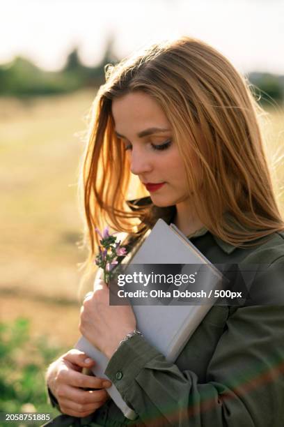 portrait of beautiful young woman relaxing in meadow with flowers - peel park stock pictures, royalty-free photos & images