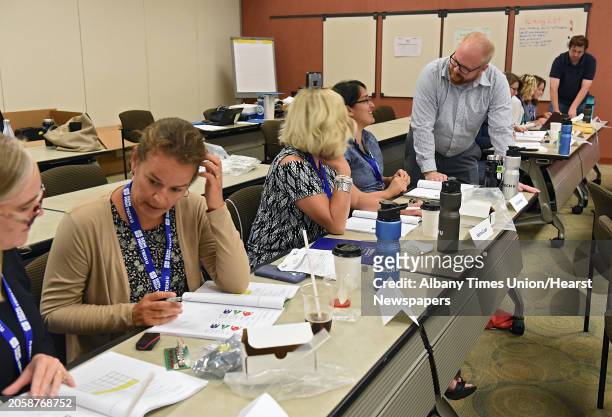Chris Tebbens of KLA, standing second to right, and Chris Netzband of SUNY Poly, right, help Capital Region teachers learn about using logic to...