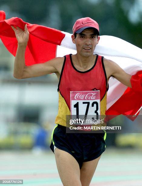 The peruvian athlete, Jesus Virueta, runs and carries the Peruvian flag, as he finishes the 42 km with a second place in Ambato, 15 September 2001...