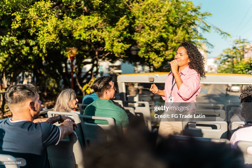 Mid adult tourist guide woman talking with tourist on tour bus