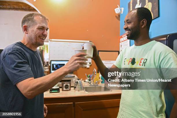 Happy Cappuccino co-owner Matt Robbins, left, makes a toast with Belayneh Woldemariam of Ethiopia who was sampling various coffees as Empower...