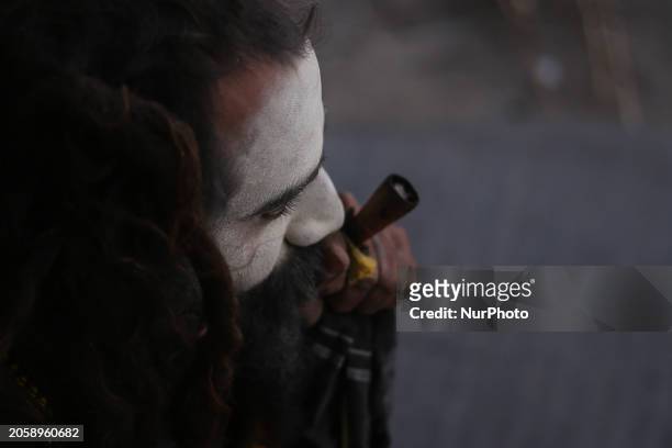 Sadhu, a Hindu holy person, is smoking marijuana from a traditional chillum on the eve of the Maha Shivaratri festival at the Pashupatinath Temple...