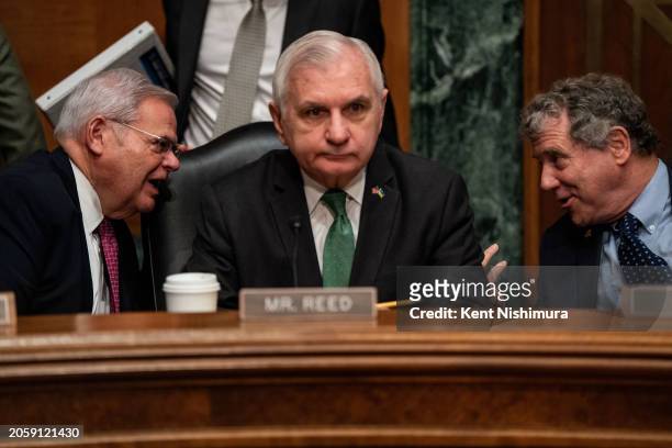Sen. Bob Menendez chats with Sen. Sherrod Brown as Sen. Jack Reed looks on before the start of a Senate Banking, Housing and Urban Affairs Committee...