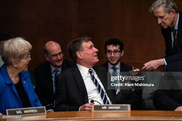 Sen. John Kennedy hands Sen. Mark Warner cash before the start of a Senate Banking, Housing and Urban Affairs Committee hearing where Federal Reserve...