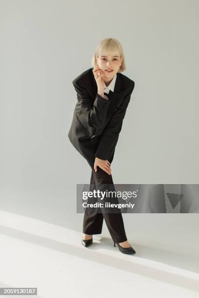 blonde woman in black suit in studio. fashion model. - black high heels stock pictures, royalty-free photos & images