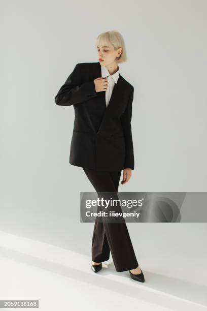 blonde woman in black suit in studio. fashion model. - black high heels stock pictures, royalty-free photos & images