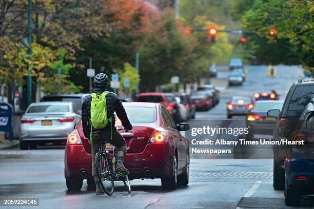 Bicyclist waits behind a car at a red light at Fulton and 4th Streets during a light rain on Wednesday, Oct. 16, 2019 in Troy, N.Y.