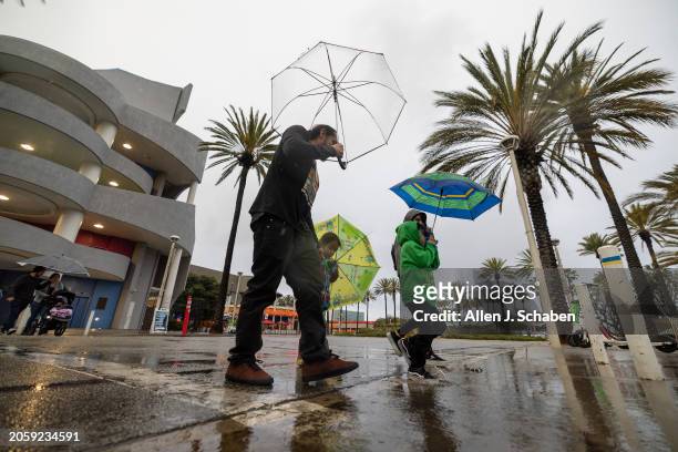 Long Beach, CA A family uses umbrellas amid a gust of wind and rain as they visit the Aquarium of The Pacific in Long Beach Wednesday, March 6, 2024.