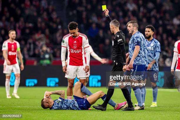 Referee Enea Jorgji shows yellow card to Tristan Gooijer of AFC Ajax, Lucas Digne of Aston Villa FC laying on the ground during the UEFA Europa...