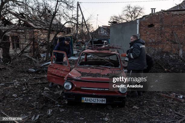 Local residents try to repair destroyed car next to heavily damaged buildings due to Russian shelling as Russia-Ukraine war continues in...