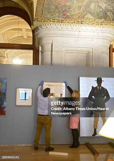Joe Madeira and Michelle Rosales, both of Office of General Services, hangs a piece of art by artist Jose Urbach titled "Reconstruction" as restored...