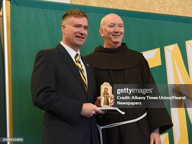 Fr. Mark Reamer, vice president for mission, guardian of the St. Bernadine of Siena Friary, gives former U.S. Rep. Chris Gibson gifts as Siena...