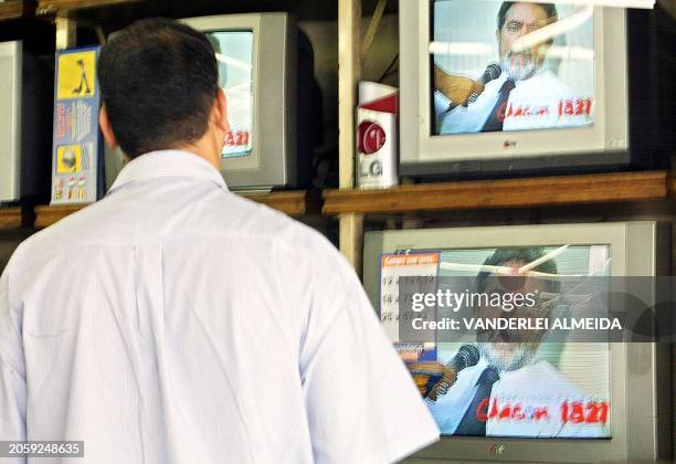 Civilian looks at Luis Inacio Lula da Silva on a TV in a store window in Rio de Janiero, 20 August 2002. Un ciudadano observa a Luiz Inacio Lula da...