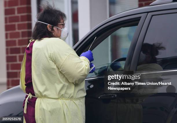 Health care worker obtains a sample from a driver at the drive-through COVID-19 testing site at the Whitney Young Administrative Building on...