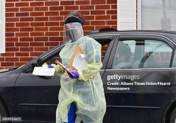 Health care worker gathers paperwork from a driver at the drive-through COVID-19 testing site at the Whitney Young Administrative Building on...