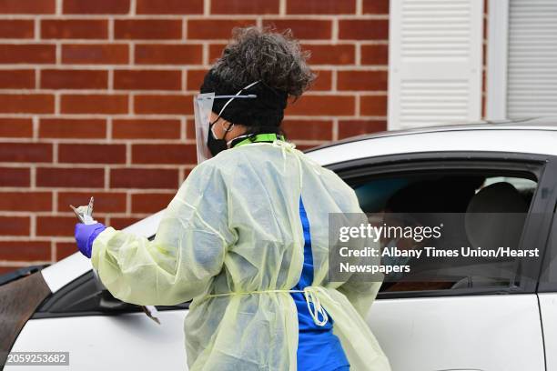 Health care worker gathers paperwork from a driver at the drive-through COVID-19 testing site at the Whitney Young Administrative Building on...