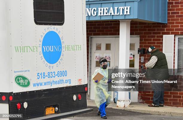 Health care worker walks out to a small line of cars at the drive-through COVID-19 testing site at the Whitney Young Administrative Building on...