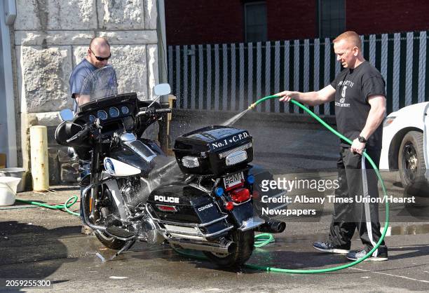 Officer Nate Meaker, left, and Sgt. Scott McKown are seen washing a police motorcycle behind the Cohoes Police Department on Wednesday, March 10,...