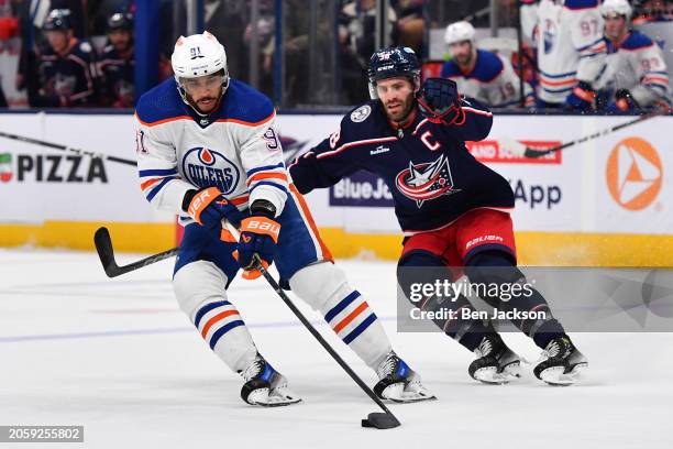 Evander Kane of the Edmonton Oilers turns the puck away from Boone Jenner of the Columbus Blue Jackets during the first period of a game at...