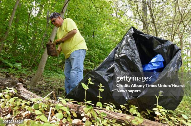 Member of the Schenectady Rotary volunteer Fred Daniels of Rotterdam finds a rusty paint can in the woods as he works with other volunteers to clean...