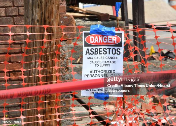 An asbestos danger sign is seen in front of the three row houses that were heavily damaged by fire last week on Tuesday, July 6, 2021 in Watervliet,...